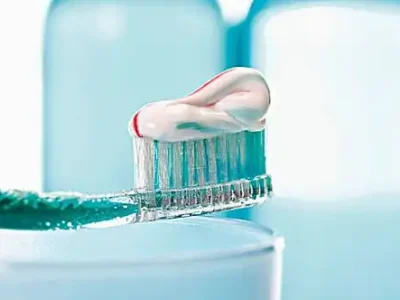 Close-up of toothpaste being squeezed onto a toothbrush, showing fresh mint paste ribbon